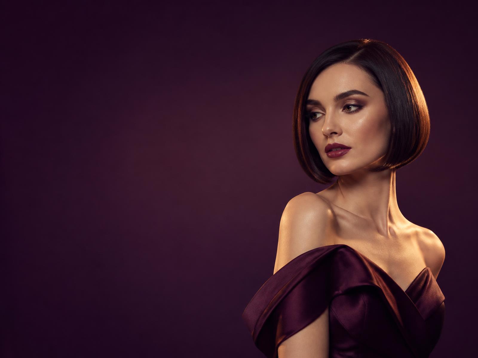 Model with defined curly hair against a plum backdrop